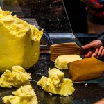 Die Butterstücke werden mit zwei Holzpaddeln geschlagen bis Wasser austritt. Die Butter beginnt zu weinen / © Foto: Georg Berg