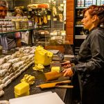 Verkaufstheke im Maison du Beurre von Jean Yves Bordier in Saint Malo. Eine Verkäuferin schlägt die Butter mit zwei Holzpaddeln / © Foto: Georg Berg