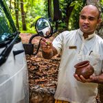 Buddhistischer Segen für eine gute Reise. Während hinten die Koffer verladen werden, sprenkelt der Hotelmanager Wasser mit Blütenblättern auf die Fahrzeugfront. Damit soll das nächste Ziel heil erreicht werden / © Foto: Georg Berg