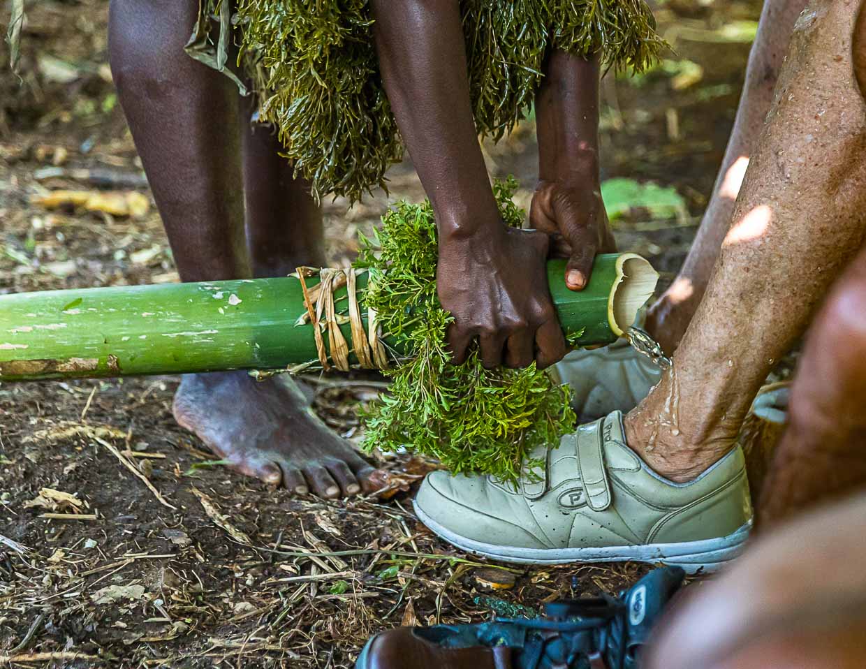 Auf ungewöhnliche Art werden Neuankömmlinge auf Bougainville willkommen geheißen. Mit Wasser aus einem Bambusrohr werden zur Inseltaufe die Füße gewaschen / © Foto: Georg Berg