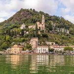 Vom Wasser aus betrachtet: Die Kirche Santa Maria del Sasso von Morcote, darunter die historische Altstadt. Viele kleine Restaurants säumen die Uferpromenade / © Foto: Georg Berg