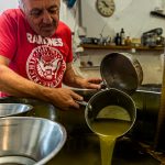 Nach dem Pressvorgang, steht das Wasser-Öl-Gemisch in offenen Behältern. Nach gut einer Stunde beginnt Fabrice Godet damit, das oben schwimmende Olivenöl abzuschöpfen. Das Fruchtwasser sinkt nach unten / © Foto: Georg Berg