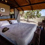 Doppelbett im australischen Outback-Chic hinter den Wellblechwänden der Bamurru Plains Lodge. Wind weht durch die Fliegengitter und keiner vermisst Klimaanlage oder WLAN / © Foto: Georg Berg