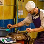 Ein Mitarbeiter der Chocolaterie Frigoulette verschließt den Mélangeur, in dem die abgewogenen Zuten gemischt und erwärmt werden. Bei Frigoulette werden keine tierischen Fette wie Milch, Sahne oder Butter verarbeitet. Auch Palmöl kommt nicht zum Einsatz. Stattdessen 68 prozentiger Kakaoanteil und echte Kakaobutter aus São Tomé / © Foto: Georg Berg