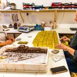 Am kühlen Vormittag wird der Bestseller der Schokoladen-Manufaktur Frigoulette von Hand in goldenes Papier verpackt. Malakoff-Pralinen, Nuss-Nougat-Pralinen mit 68  Kakaoanteil und gerösteten Haselnüssen. Im Sommer läuft die Produktion für Weihnachten. Frigoulette beliefert Geschäfte in ganz Frankreich mit Malakoff-Pralinen / © Foto: Georg Berg