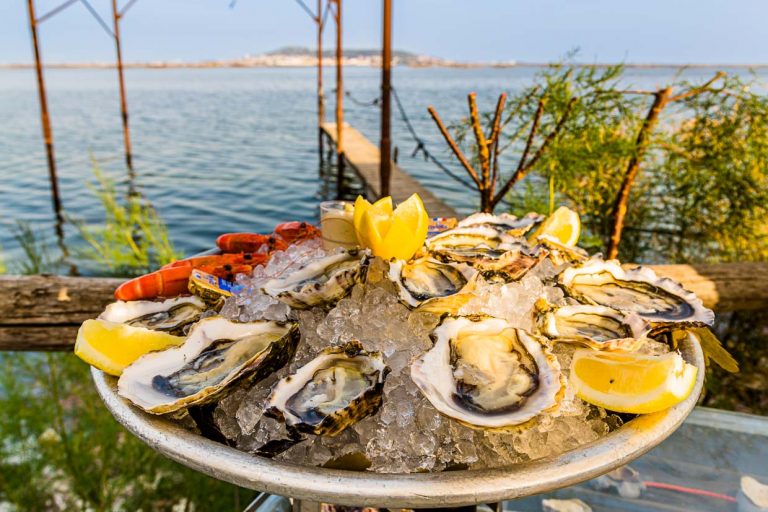 Austernplatte mit Meeresfrüchten im Strandpavillion Le St Pierre Tarbouriech. Hinter der Lagune liegt die Stadt Sète / © Foto: Georg Berg