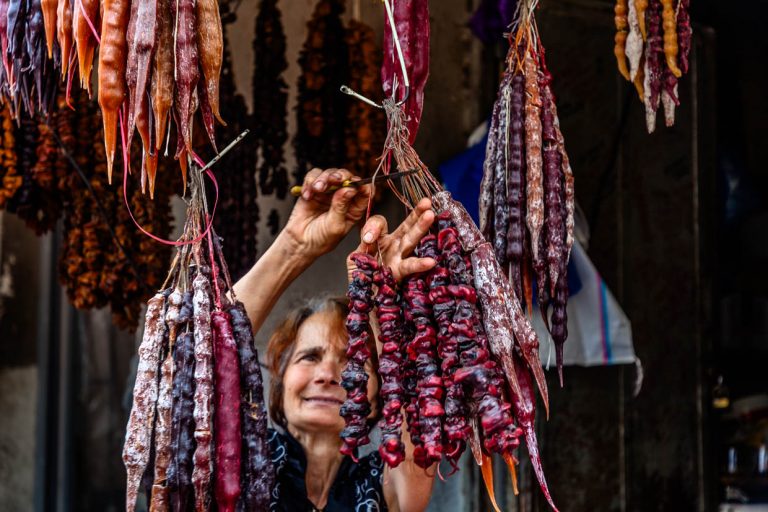 A saleswoman cuts sticks from Churchkhela. Churtschchela (ჩურჩხელა) is a Georgian confectionery. Nuts coated with pelamushi, a chocolate coating made from boiled grape juice with starch flour without sugar / © Photo: Georg Berg
