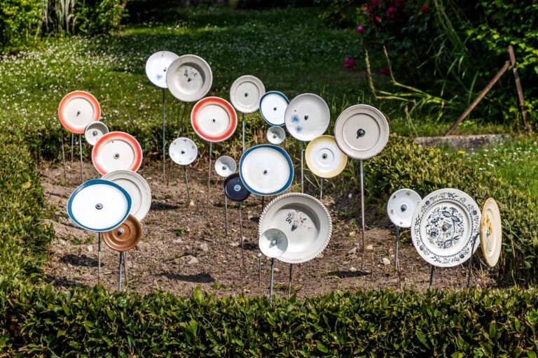 Plates on poles in a front garden in France, Nouvelle-Aqutaine. The motif matches the German proverb "Über den Tellerrand schauen" (think outside the box) and refers to an open, curious attitude in which one is prepared to cross one's own boundaries and learn new things. The phrase is often used in connection with cosmopolitanism, a change of perspective or innovation / © Photo: Georg Berg