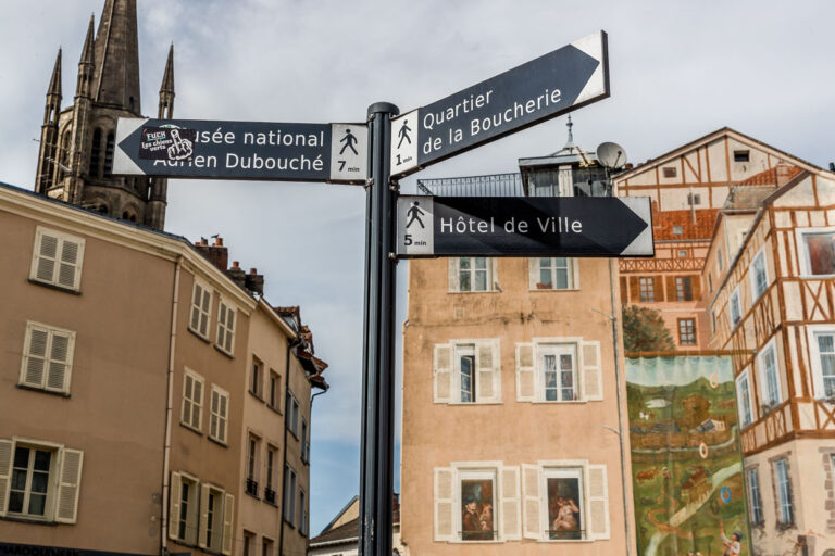 Signs in the center of Limoges pointing to the city's sights, such as the Musée National Adrien Dubouché, the butcher's quarter and the town hall, in the background a mural in the style of the old half-timbered houses / © Photo: Georg Berg