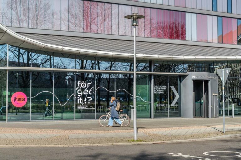 Frau fährt Fahrrad vor dem Deutschen Buch- und Schriftmuseum in Leipzig, Germany